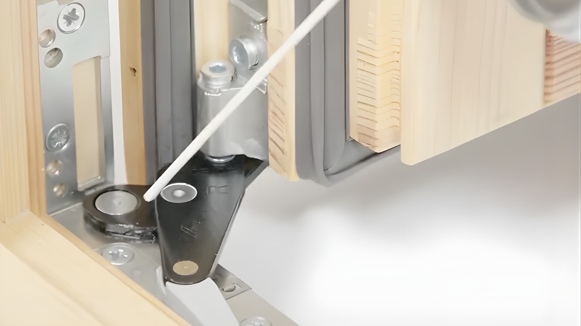 Smarowanie zawiasu ukrytego w systemie Roto NXC przy pomocy aplikatora – pielęgnacja okuć w oknie drewnianym.